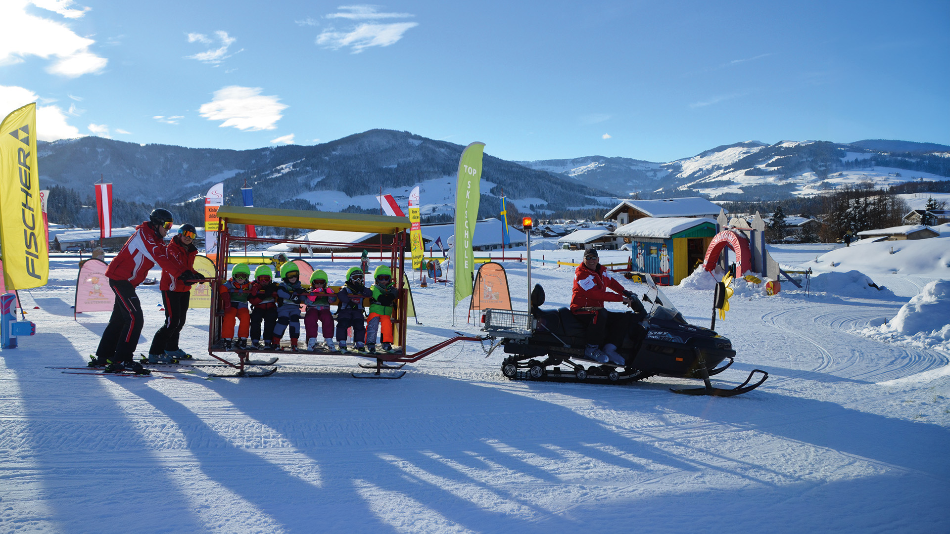 Kinder werden im Kinderland mit dem Schneemobil transportiert und haben beim Skifahren lernen viel Spass in Westendorf